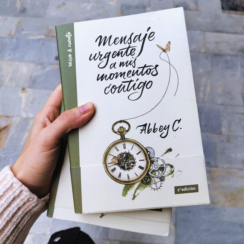 La mano de la autora sostiene su primer poemario titulado Mensaje urgente a mis momentos contigo