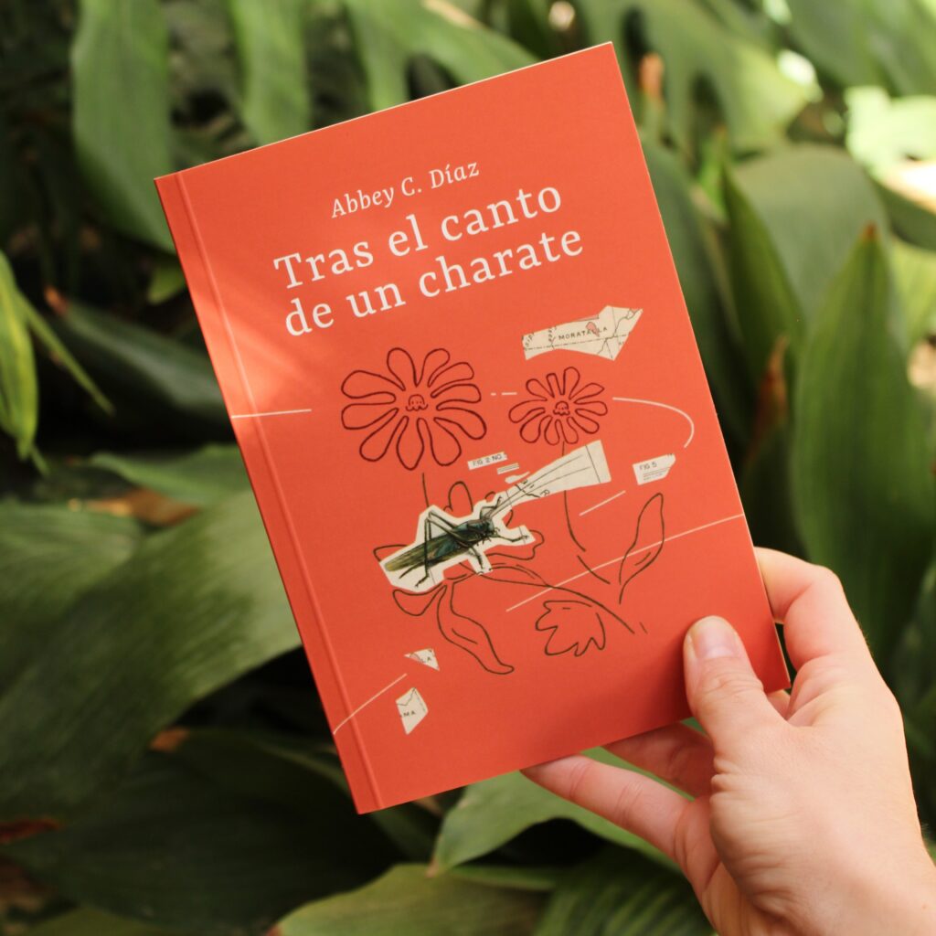 La mano de la autora sostiene su tercer poemario titulado Tras el canto de un charate